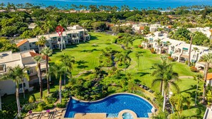 Un resort con piscina, exuberante vegetación y vista al océano.