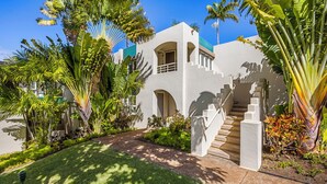 Un edificio moderno con una escalera central, rodeado de exuberante vegetación tropical.