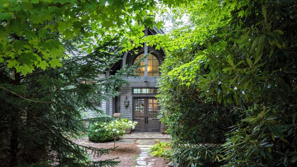 A stone pathway leading to a building with a dark wooden door and arched windows, surrounded by dense greenery. - Elegant interior. Sunset views. Walk to town. Professional kitchen. Pet friendly (Highlands)