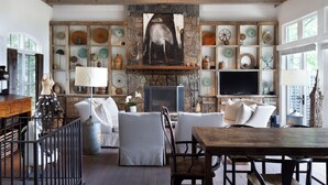 A spacious living room with a stone fireplace, white sofas, and a wooden dining table. - Elegant interior. Sunset views. Walk to town. Professional kitchen. Pet friendly (Highlands)