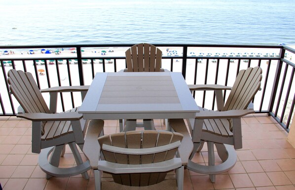 Une table et des chaises sur un balcon avec vue sur la plage.