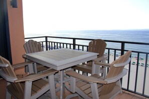 Un balcon avec une table et des chaises donnant sur une plage.