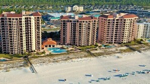Un hôtel situé en bord de mer, composé de plusieurs immeubles de grande hauteur, doté d’une piscine centrale et d’une zone de plage.