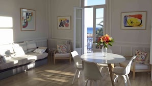 A bright living room with a sofa, chairs, a dining table, and artwork on the walls. - Blue Riviera: a splendid beachfront 1-bedroom apt w/stunning view (Menton)