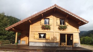A wooden chalet with a stone foundation, wooden shutters, and flower boxes on the windows. - Chalet Érable**** - Sauna - 8 Pers | Household, Towels & Beds Made Included (Rochesson)