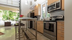 Una cucina moderna con elettrodomestici in acciaio inossidabile, un carrello e vista sull'esterno.