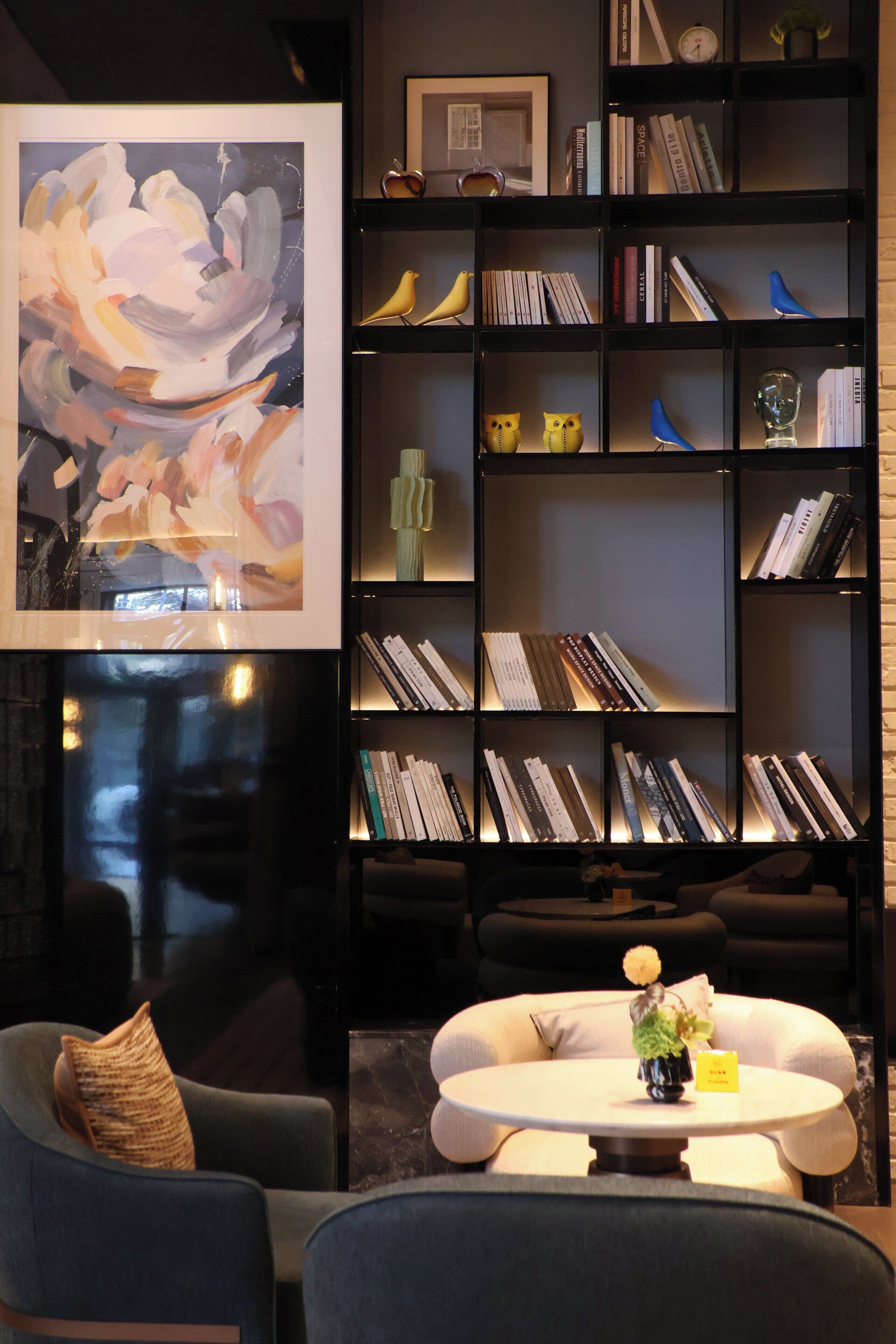 Ein stilvolles Wohnzimmer mit Bücherregal, einem Gemälde und einem Couchtisch.