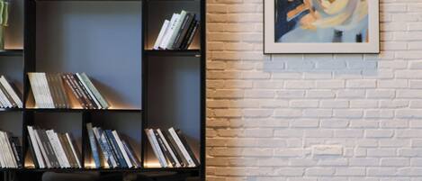 A modern living room with a fireplace, a bookshelf filled with books, and a large abstract painting on the wall.