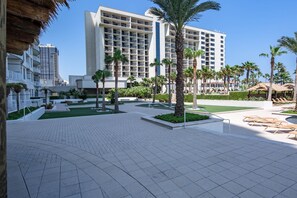 Experience the tranquil courtyard with a large building, lush garden, and comfortable seating area.