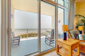 Enjoy a beach view from the balcony with a sliding glass door, featuring a chair and table.
