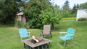 A garden with a fire pit table, two blue patterned chairs, and a wooden structure in the background. - Water front property with spectacular views.  (Marrowstone)