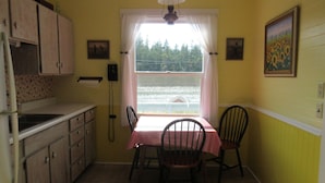 A kitchen with a window, a table with a checkered tablecloth, and two chairs. - Water front property with spectacular views.  (Marrowstone)