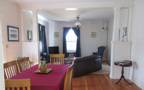 Un comedor con una mesa dispuesta para cuatro, un televisor y un sofá al fondo.