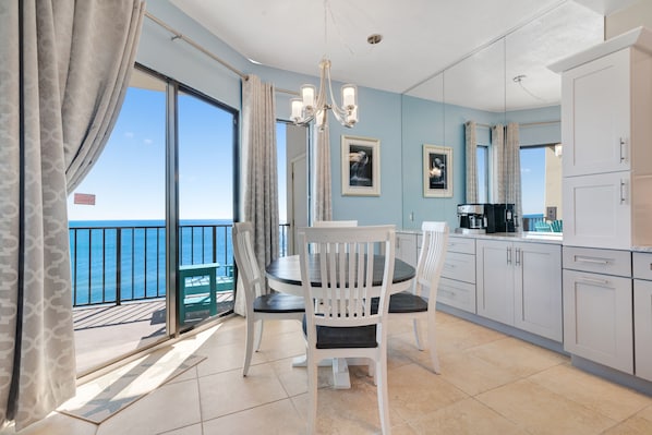 Enjoy a room with a large window offering a view of the sea, a dining area, kitchenette, and chandelier.
