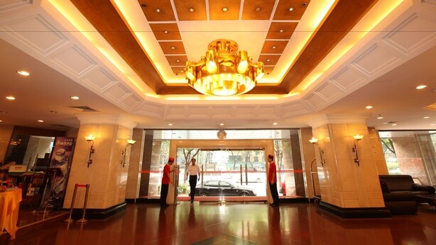 A hotel lobby with a large chandelier, a reception desk, and a waiting area with a sofa. - Oriental Silk Hotel - Guangzhou (Guangzhou)