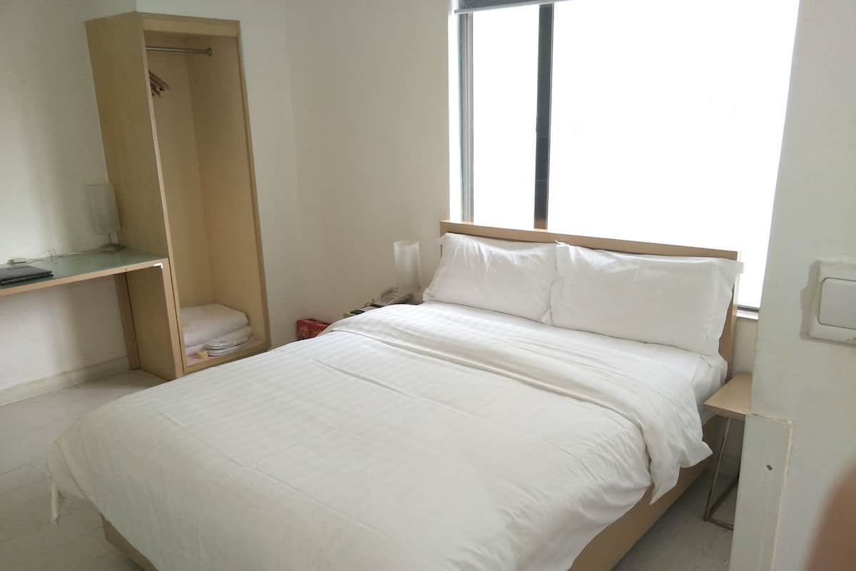 Quarto com cama, mesa de cabeceira, guarda-roupa e janela.