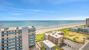 Ett hotell vid stranden med flera byggnader, en sandstrand och en klarblå himmel.