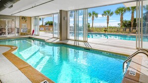 Una piscina interior con paredes de vidrio transparente, una silla de salvavidas y un cartel que indica que está prohibido sumergirse.