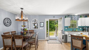 A dining area with a wooden table and chairs, a chandelier, and a fruit basket. - Best Lakefront Views, NEW Hot Tub, FirePit, Dock, Kayaks, Dog Friendly (Dandridge)