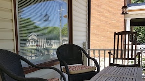 Une véranda avec des fauteuils en osier et une table en bois.