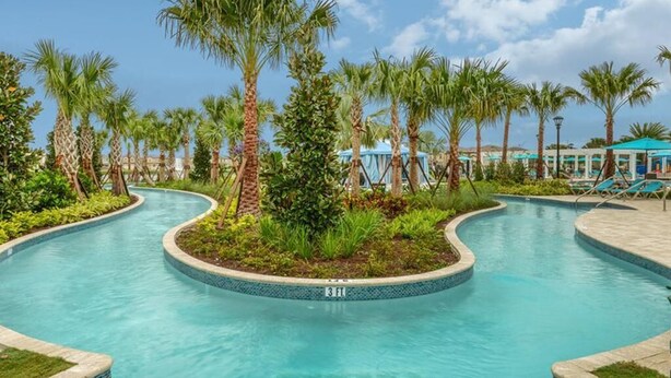 Piscina com design curvo, rodeada por palmeiras e vegetação.