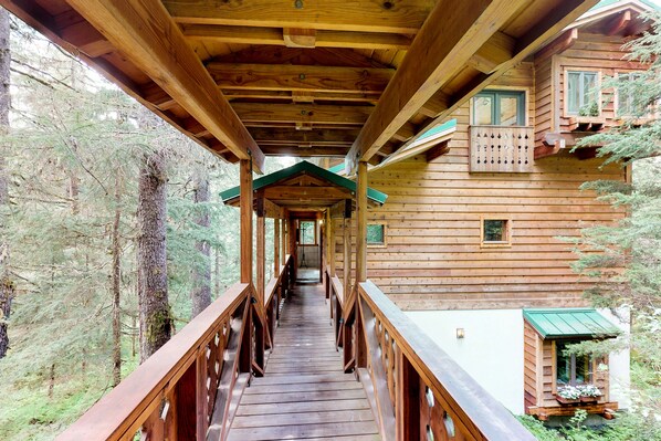 Surrounded by a forest, this cabin features a wooden deck and multiple windows.