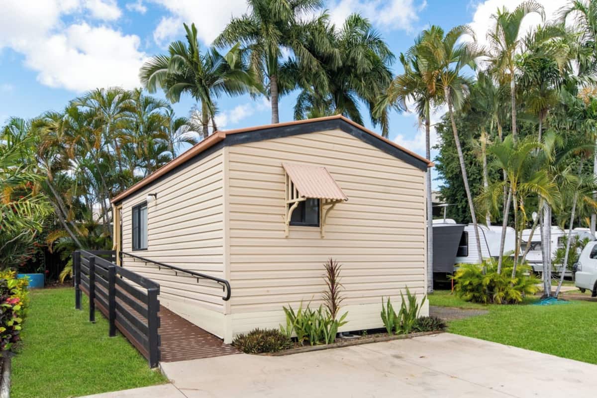 A single-story mobile home with a beige exterior, a small window, and a porch with a black railing.
