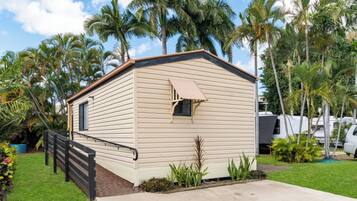 A single-story mobile home with a beige exterior, a small window, and a porch with a black railing.