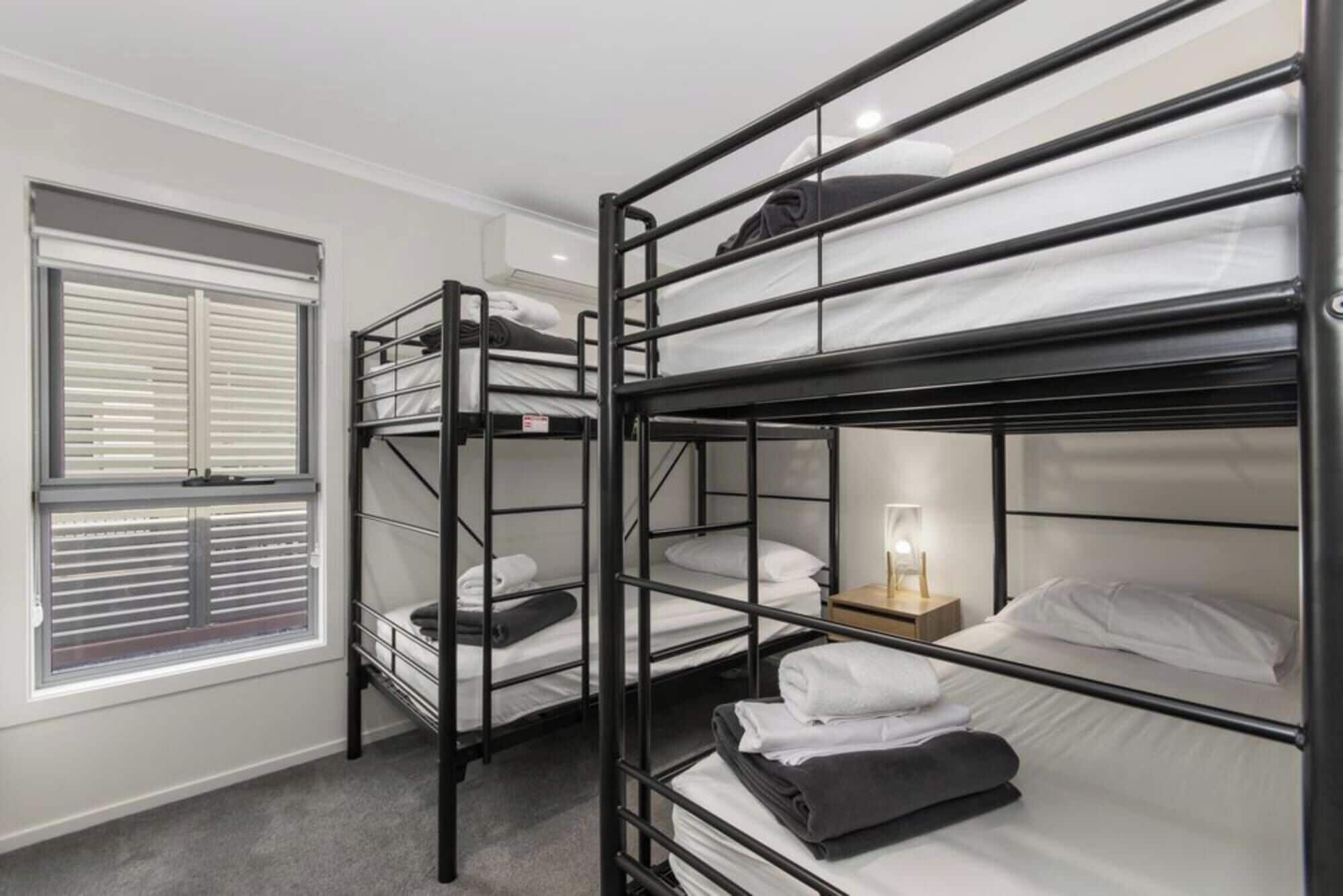 A bunk bed room with a window and a bedside table with a lamp.