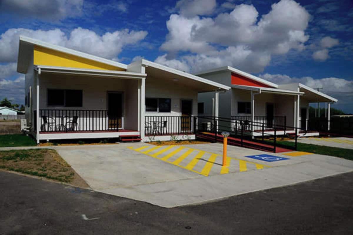A row of single-story buildings with a covered porch, a wheelchair-accessible ramp, and a parking lot with marked spaces.
