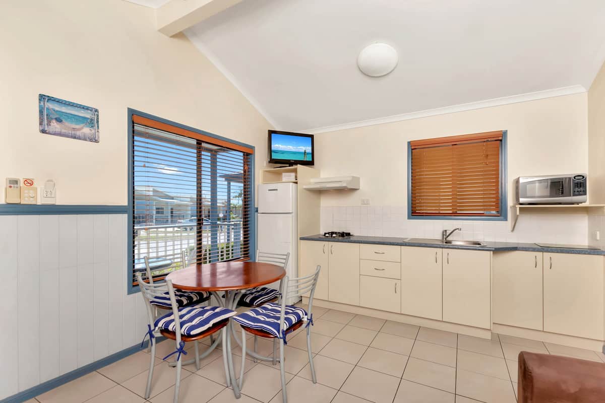 A compact kitchen with a dining area, a television, and a microwave.