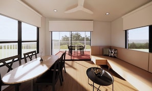 A modern interior with a dining table, chairs, a sofa, and large windows offering views. - Discovery Parks - Townsville (Wulguru)