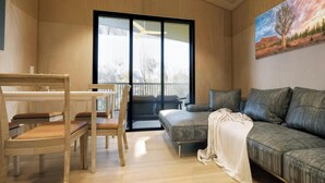 A modern living room with a wooden dining table, chairs, a sofa, and a large window. - Discovery Parks - Townsville (Wulguru)