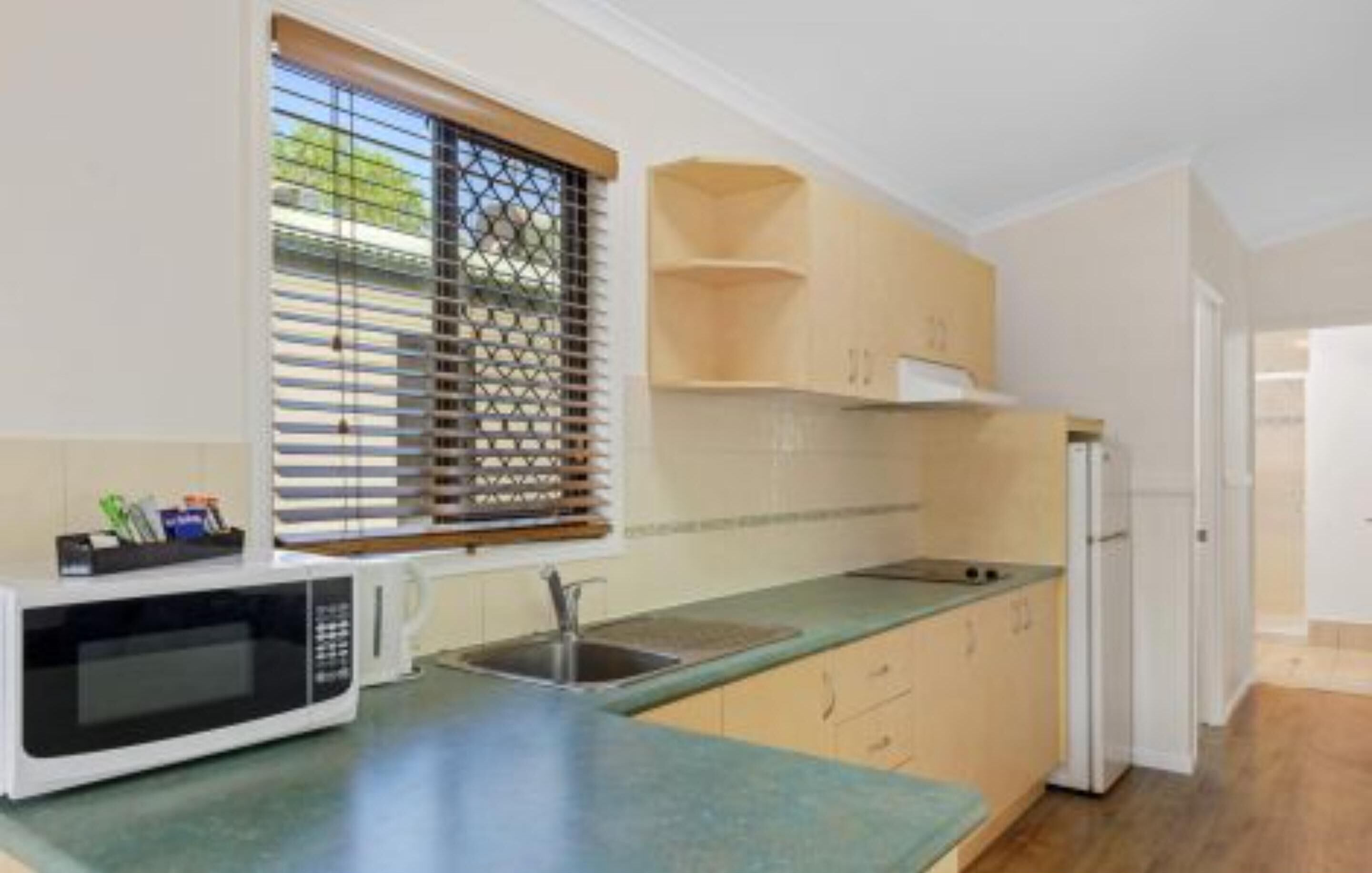 A kitchen with a microwave, sink, and cabinets.