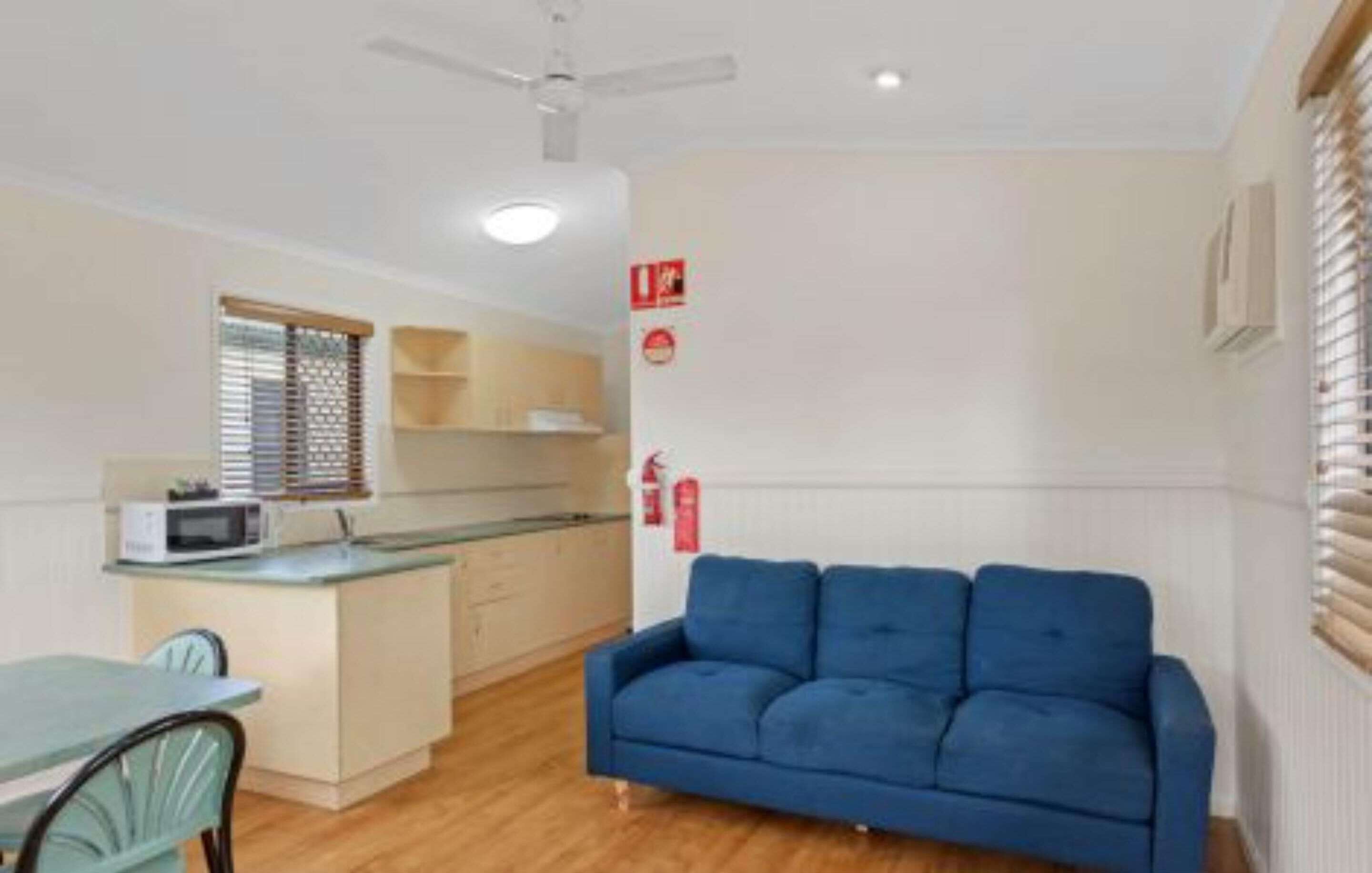 Un espacio habitable compacto con kitchenette, comedor y un sofá azul.
