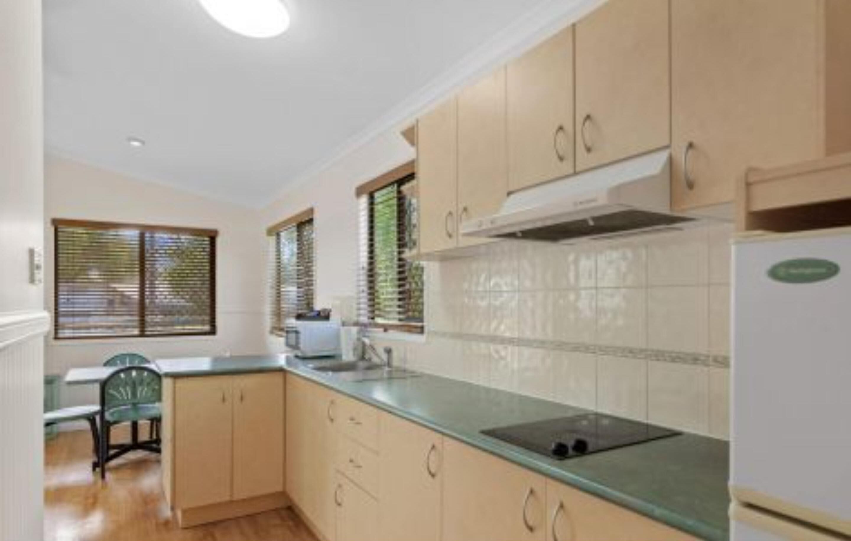 A kitchen with light wooden cabinets, a green countertop, and a built-in oven.