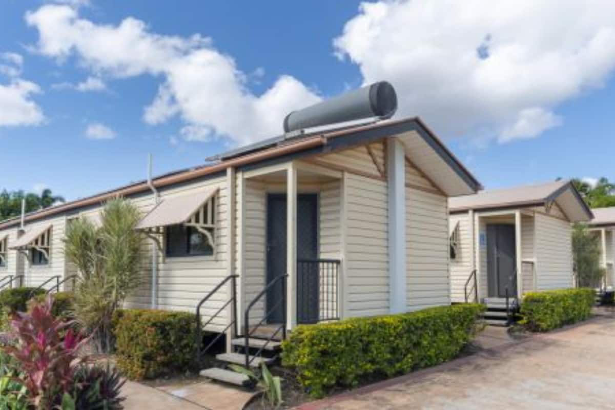 A single-story mobile home with a covered porch, a small front yard with a pathway, and a clear sky.