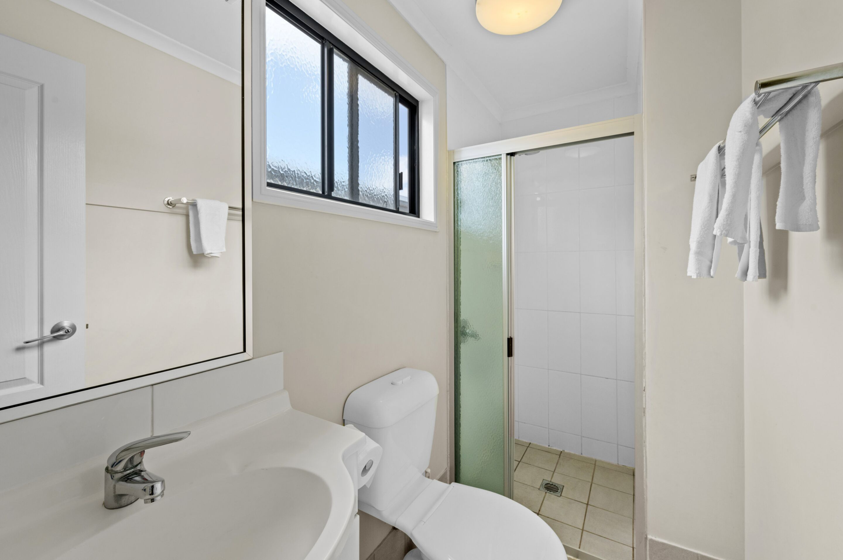 Ein Badezimmer mit Toilette, Waschbecken und einer Duschkabine aus Glas.