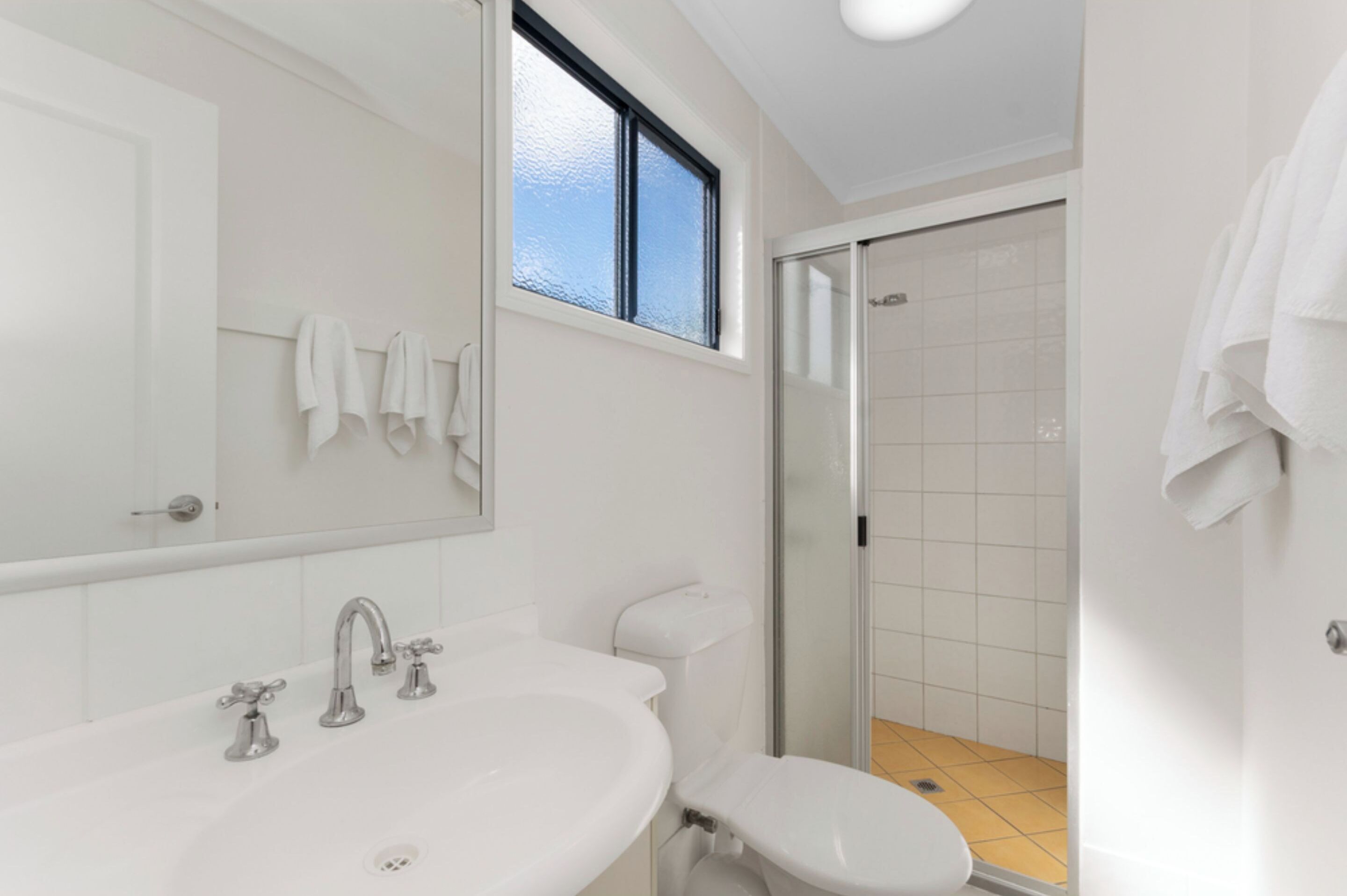 Un baño con lavamanos blanco, inodoro y zona de ducha.