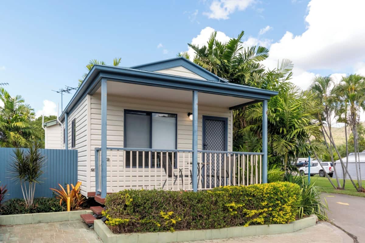 A single-story house with a porch, surrounded by tropical vegetation.