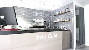 A modern Info Café with a black countertop, grey tiled walls, and a flat-screen TV. - HAH Guesthouse (Seoul)