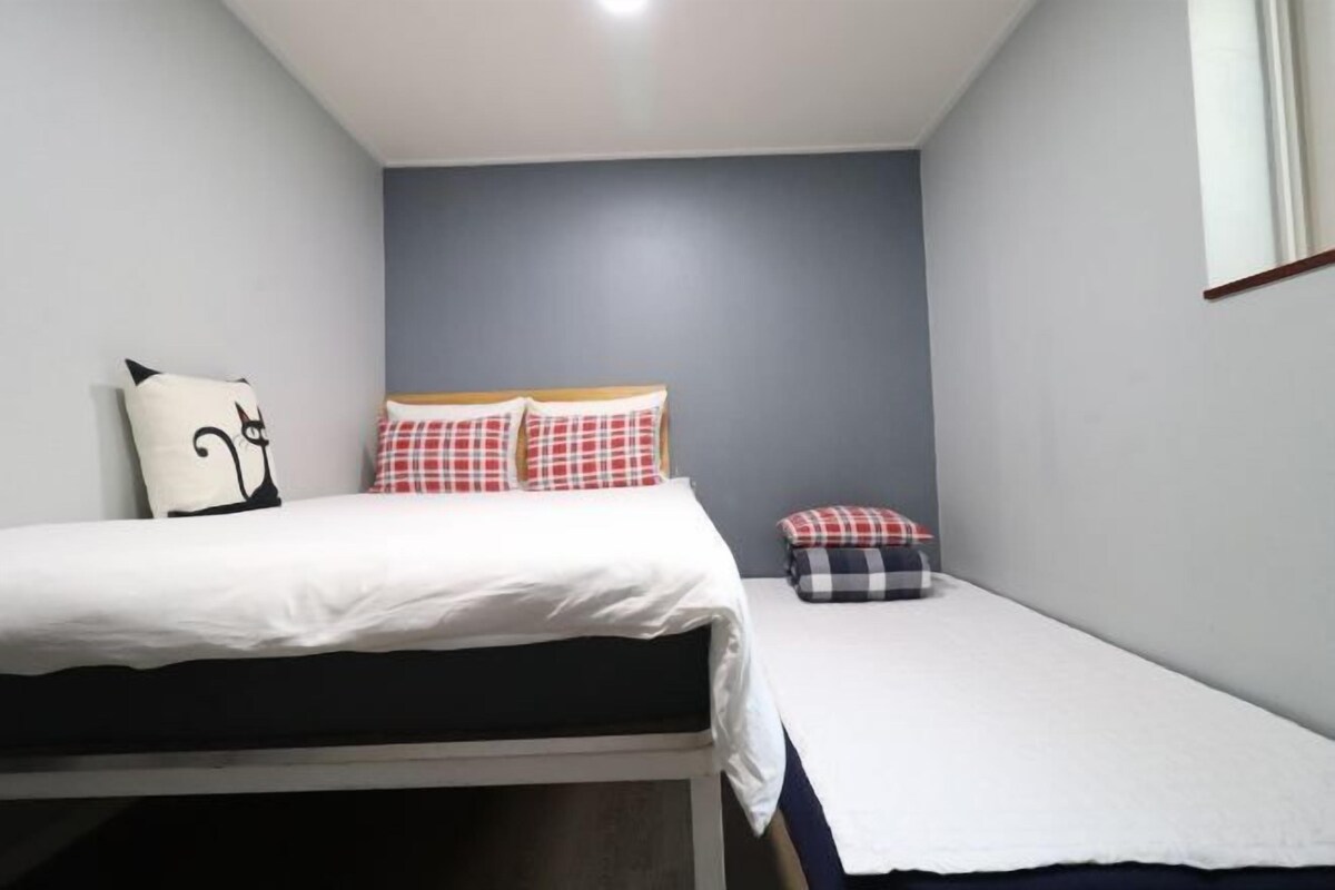 A small, neatly arranged bedroom with a bed, a bedside table, and a chair.
