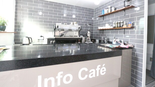 A modern café interior with a black countertop, grey tiled walls, and a coffee machine. - HAH Guesthouse (Seoul)