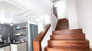A kitchen with a wooden staircase leading to a landing. - HAH Guesthouse (Seoul)