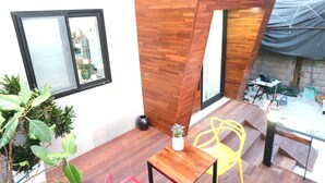 A modern interior with a wooden accent wall, a small table with a potted plant, and a yellow chair. - HAH Guesthouse (Seoul)
