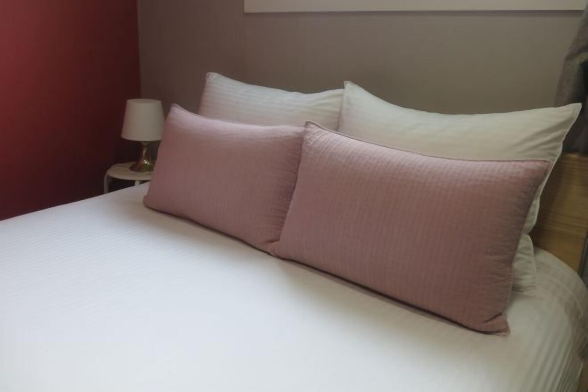 A bed with two pillows and a bedside table with a lamp.