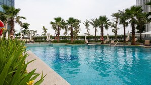 A swimming pool with palm trees and lounge chairs. - Vinhomes Central Park - MM Home (Ho Chi Minh City)