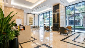A modern lobby with a reception desk, seating area, and large windows offering views of the outdoors. - Vinhomes Central Park - MM Home (Ho Chi Minh City)