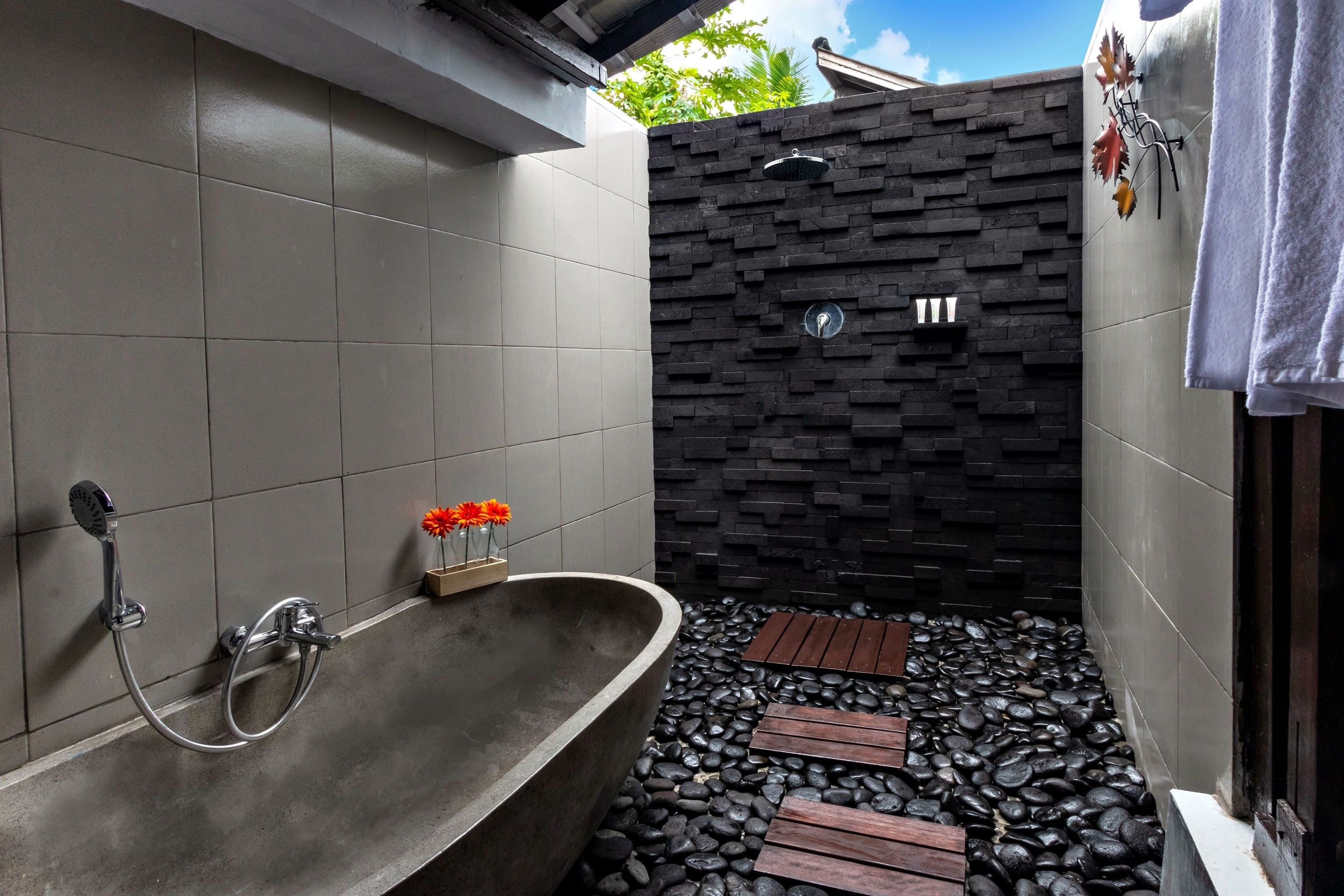 A modern bathroom with a freestanding bathtub, a shower head, and a decorative wall.