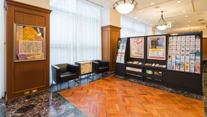 A lobby with a wooden herringbone floor, black leather chairs, a reception desk, and a wall with informational displays. - JR East Hotel Mets Mito (Mito)